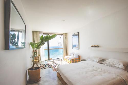 a bedroom with a bed and a window with a plant at Amouage by Surf Maroc in Taghazout