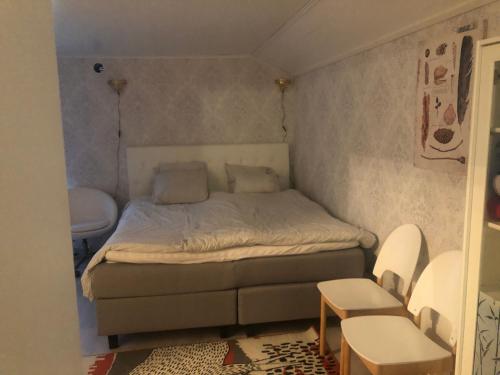 a small bedroom with a bed and two chairs at Puutaloasunto 1 km Turun Aurajoelta föriltä in Turku