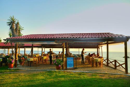 a group of people sitting at a restaurant on the beach at Christinas lofts in Ágios Matthaíos