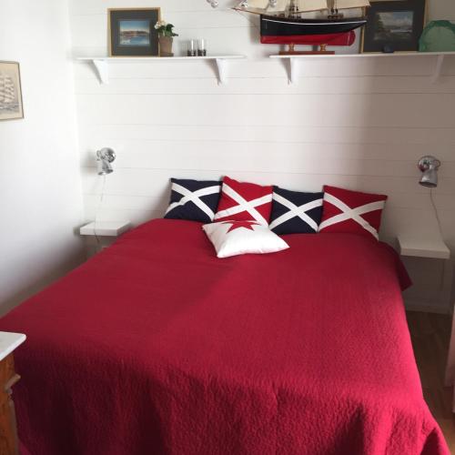 a bedroom with a red bed with four pillows at Peaceful Cottage in Gothenburg
