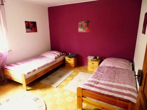 - 2 lits dans une chambre aux murs violets dans l'établissement Ferienwohnung Hermann, à Spangenberg