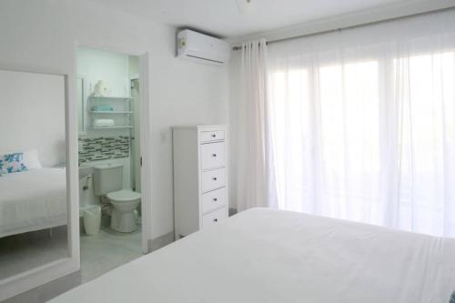 a white bedroom with a bed and a bathroom at Sea Glass Villa - Spacious 2 Bedroom, 2 Bathroom in Saint James