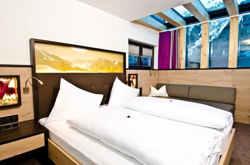 una camera da letto con un grande letto bianco e finestre di Astellina hotel-apart a Ischgl