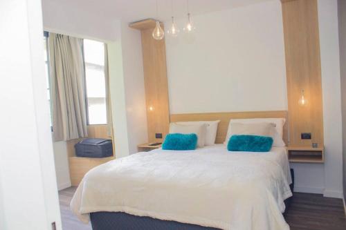 1 dormitorio con 1 cama blanca grande con almohadas azules en RecoBerta Apartment. Diseñado para disfrutar en Buenos Aires