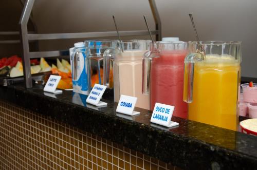 a counter with different colored drinks in glass jars at Ilhabela Park Hotel in Brasilia