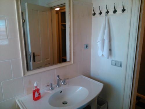 ein weißes Badezimmer mit einem Waschbecken und einem Spiegel in der Unterkunft Joosti Puhkemaja in Tõutsi
