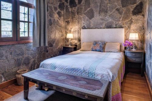 1 dormitorio con cama y pared de piedra en Luxury villa in Nature with Swimming pool Luxus-Finca in der Natur mit pool, Finca de lujo en la naturaleza con piscina, en El Retamar
