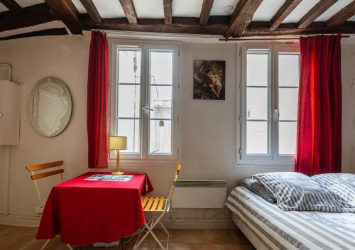 une chambre avec un lit, une table et des fenêtres dans l'établissement Appartement Mouffetard, à Paris