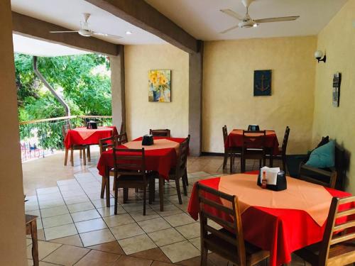 a restaurant with red tables and chairs and a large window at Hotel Casa Esmeralda in Sámara