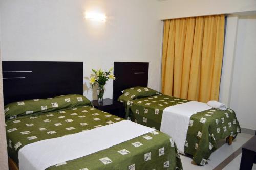 Habitación de hotel con 2 camas con sábanas verdes y blancas en Porto Hotel, en Lázaro Cárdenas