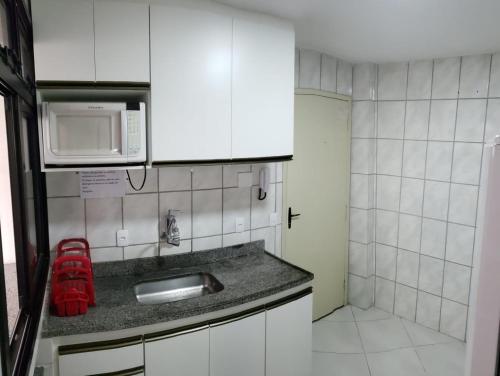 una pequeña cocina con fregadero y microondas en Apartamento Residencial Angélica em Guarapari a 150m do mar, en Guarapari