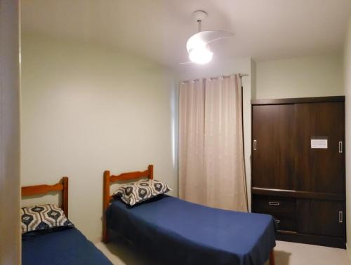 a bedroom with two beds and a cabinet at Apartamento Residencial Angélica em Guarapari a 150m do mar in Guarapari