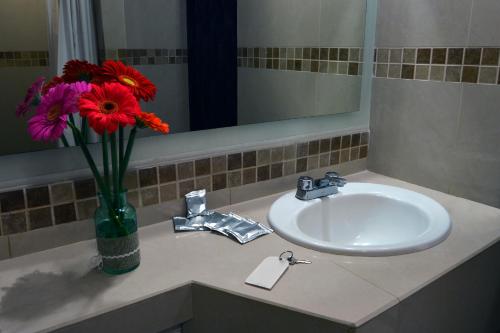 ein Waschbecken mit einer Vase mit Blumen im Bad in der Unterkunft Porto Hotel in Lázaro Cárdenas
