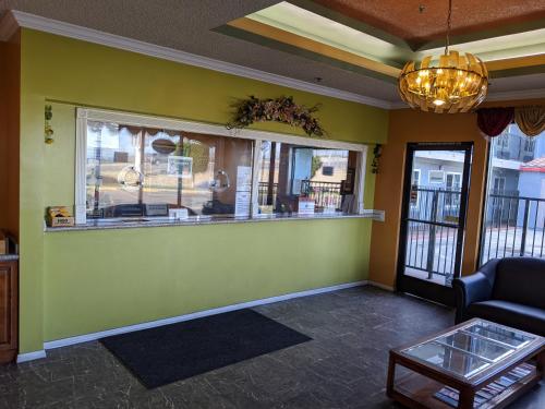 una sala de espera con una pared verde y un mostrador en Passport Inn & Suites, en Corona