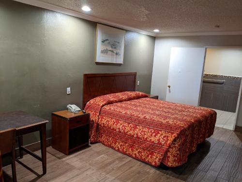 コロナにあるPassport Inn & Suitesのベッドとテーブルが備わるホテルルームです。