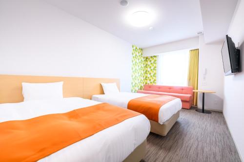 a hotel room with two beds and a tv at Hotel Sobial Namba Daikokucho in Osaka
