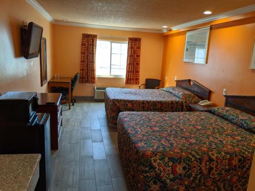 コロナにあるPassport Inn & Suitesのベッド2台とデスクが備わるホテルルームです。