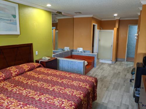 a hotel room with a bed and a bathroom at Passport Inn & Suites in Corona