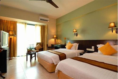 a hotel room with two beds and a television at Beringgis Beach Resort & Spa in Papar