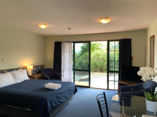 Schlafzimmer mit einem Bett und einer Glasschiebetür in der Unterkunft Studio 3 - Central to Kaikoura! in Kaikoura