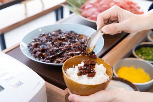 a person is spooning food into a bowl of food at Vessel Inn Keisei Tsudanuma Station in Narashino