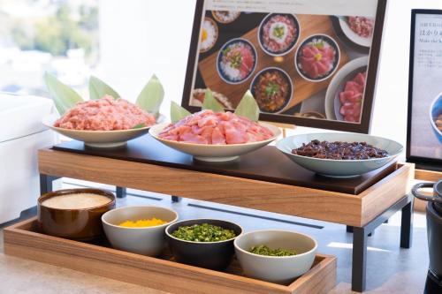 a buffet with bowls of different types of food at Vessel Inn Keisei Tsudanuma Station in Narashino