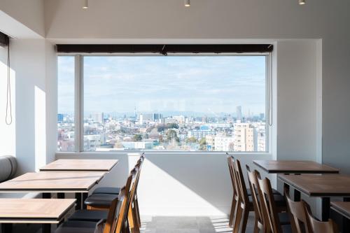 a room with tables and chairs and a large window at Vessel Inn Keisei Tsudanuma Station in Narashino