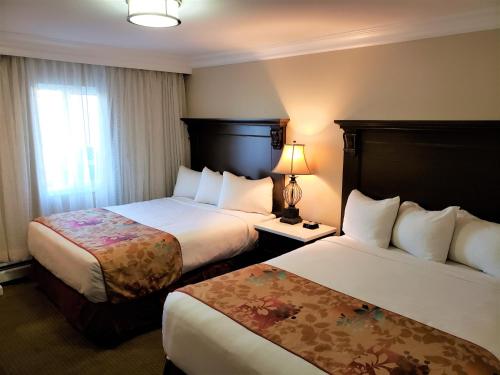 um quarto de hotel com duas camas e uma janela em Arbutus Inn em Victoria