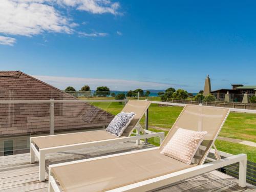 two chairs and a table on a deck at Coastal Pearl - Matarangi Holiday Home in Matarangi