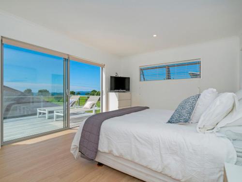 ein Schlafzimmer mit einem großen Bett und einem Balkon in der Unterkunft Coastal Pearl - Matarangi Holiday Home in Matarangi