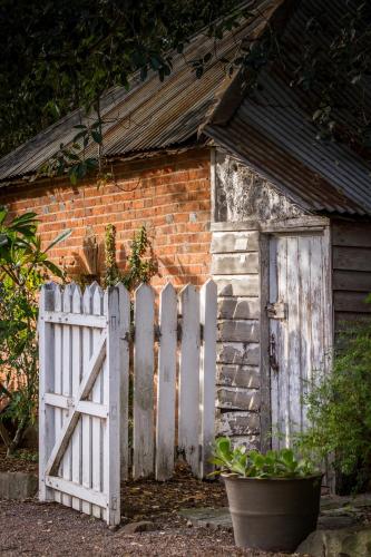 an old house with a white gate and a brick building at The Barracks, Tocal in Paterson