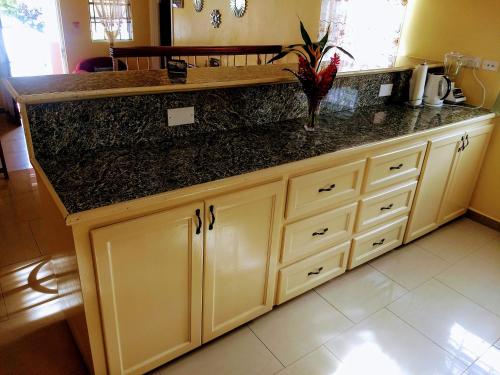 a kitchen with white cabinets and a black counter top at BenCastle Villa in Gros Islet