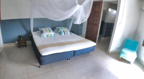 a bedroom with a bed with a canopy and pillows at Infiniti Blue in Bouillante