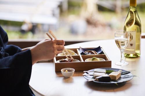a table with a box of food and a glass of wine at Takamiya Ryokan Sagiya Sansorai in Kaminoyama