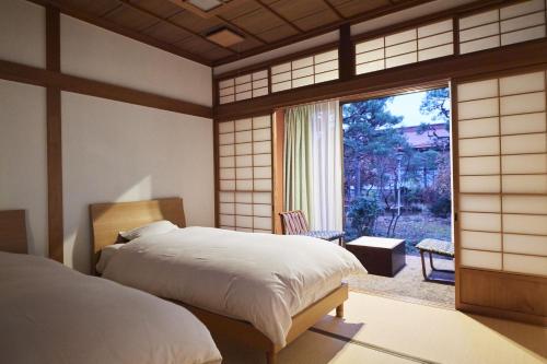 1 dormitorio con 2 camas y ventana grande en Takamiya Ryokan Sagiya Sansorai en Kaminoyama