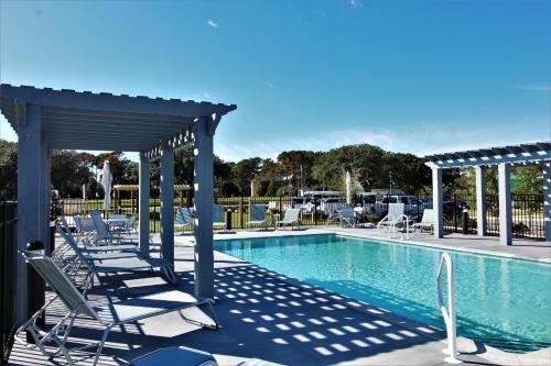 a swimming pool with lounge chairs and a pavilion at Beacon Quarters by KEES Vacations in Corolla