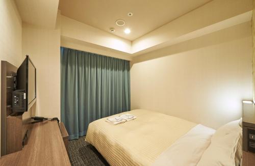 a hotel room with a bed and a television at Sotetsu Fresa Inn Nagoya Sakuradoriguchi in Nagoya