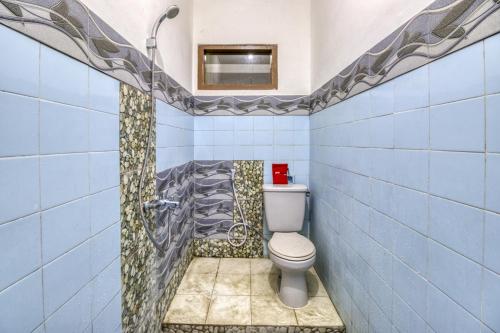 uma casa de banho em azulejos azuis com um WC e um chuveiro em RedDoorz Hostel near Adisucipto Airport Yogyakarta em Yogyakarta