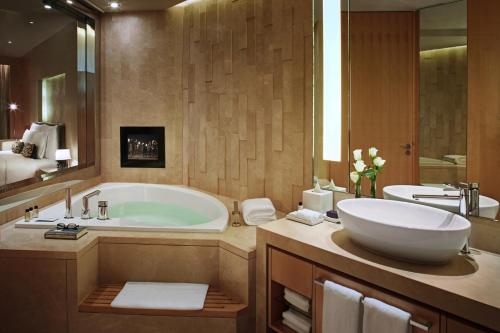 a bathroom with a large tub and a sink at The Meydan Hotel Dubai in Dubai