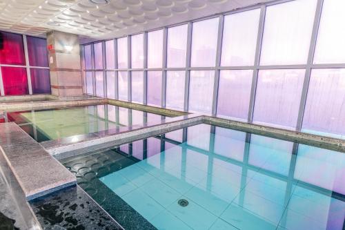 a swimming pool in a building with windows at The Blue Sky Hotel and Tower in Ulaanbaatar