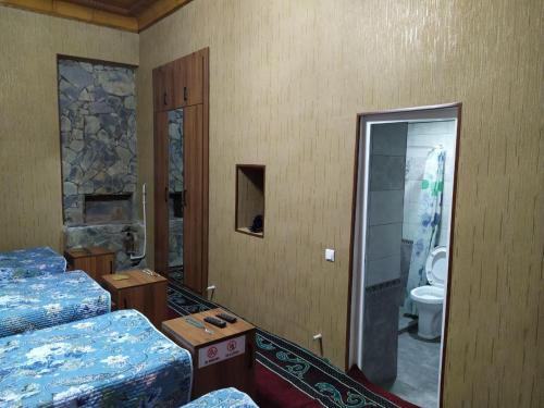a room with two beds and a bathroom with a toilet at Uvaysiy family guest house in Margilan