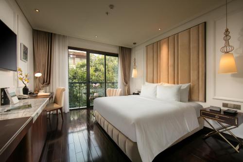 a hotel room with a large bed and a desk at Anatole Hotel Hanoi in Hanoi