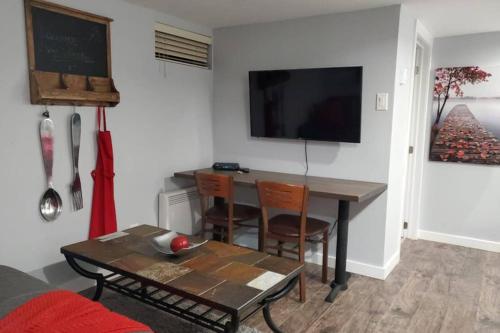 a living room with a table and a television on a wall at 1-Bedroom Mi Casita by Amazing Property Rentals in Gatineau