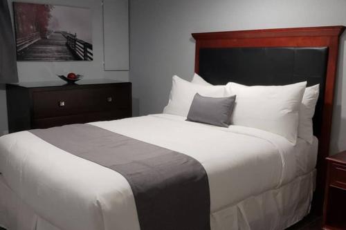 um quarto com uma cama grande com lençóis brancos e almofadas em 1-Bedroom Mi Casita by Amazing Property Rentals em Gatineau