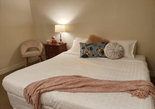 a bedroom with a white bed with a blanket on it at The Lancefield Lodge in Lancefield
