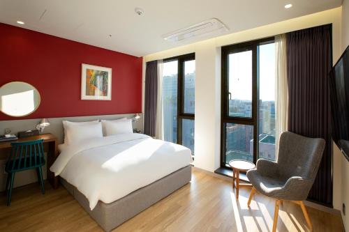 a bedroom with a white bed and a red wall at Hotel Arte in Suwon