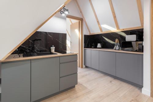a kitchen with white cabinets and black counter tops at Osada Gubałówka na Polanie Pająkówka & SPA in Kościelisko