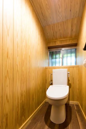 a bathroom with a white toilet in a wooden wall at Guest House Maru in Kashima