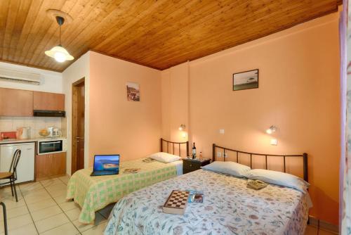 a bedroom with two beds and a kitchen with a laptop at Christinas apartments in Ágios Matthaíos