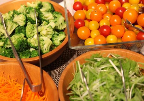 a table topped with bowls of vegetables and fruits at Urban Hotel Minami Kusatsu in Kusatsu